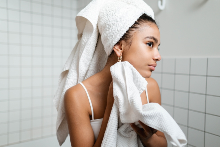 A woman in a bathrobe drying her face