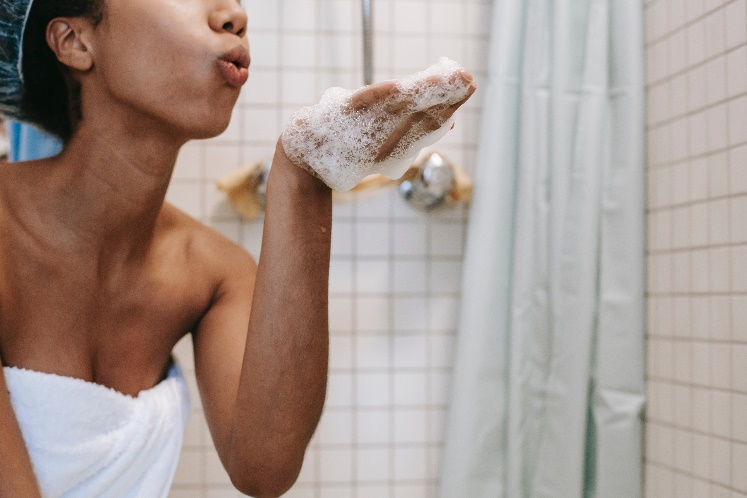 A person blowing shampoo foam off their hand