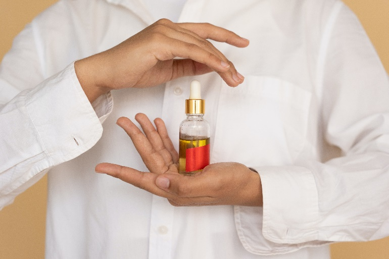 A person holding a skincare product in a dropper bottle