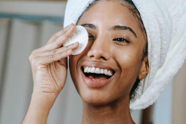 A person wiping their face with a cotton pad
