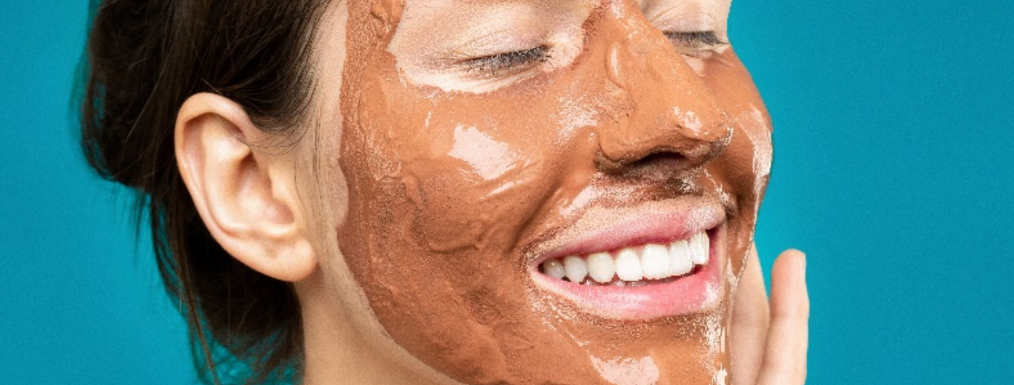 A smiling woman happily applying a rich DIY face masks, glowing with confidence and enjoying her at-home skincare ritual.