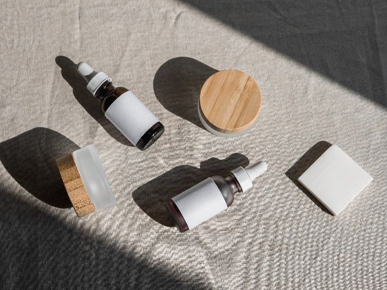 Cosmetic containers strawn on a grey cloth.